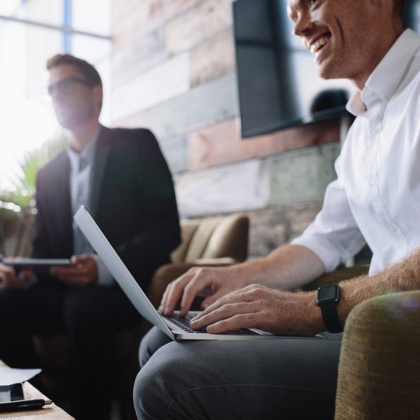 Businessman using laptop in meeting with corporate colleagues